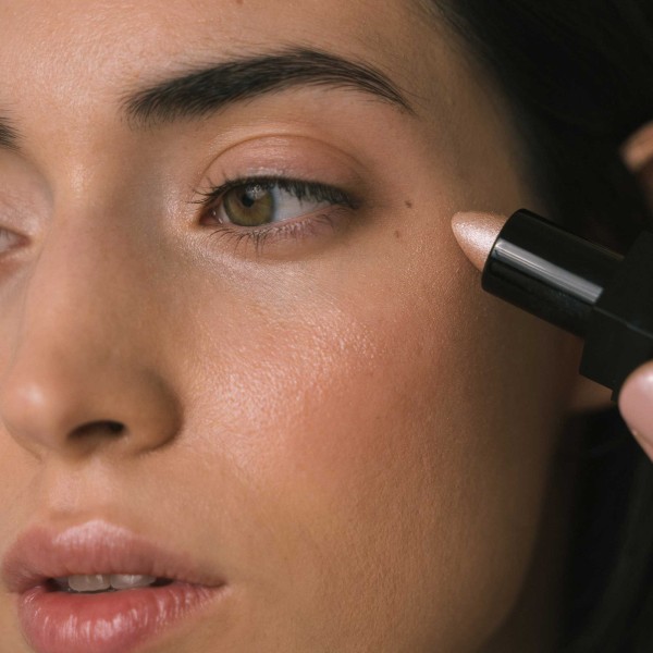 Perfil de mujer aplicando iluminador color rosa intenso