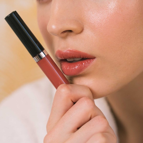 Woman lips close-up wearing lip gloss Glossy Coral color