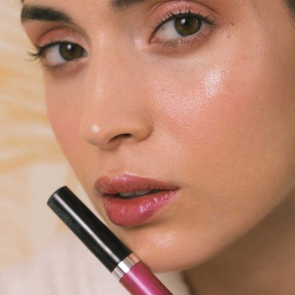 Labios de mujer close-up llevando brillo de labios color rosa intenso